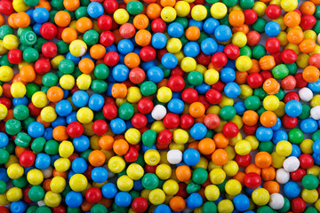 Colorful background of assorted shiny round gumballs. Background photo of multicolored gumballs. A lot of gum sweet candy. Photo of candy taken inside candy specialty store.