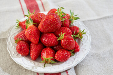 Plate with french organic red ripe sweet strawberries Fraises de Plougastel, harvested in France
