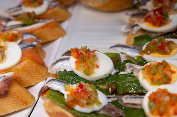 Typical snack of Basque Country, pinchos or pinxtos skewers with small pieces of bread, sea food, eggs, cheese, jamon served in bar in San-Sebastian or Bilbao, Spain, close up
