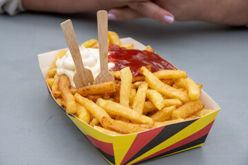 Belgian street and fast food, paper box in colors of Belgian flag with fried potato frit chips and...