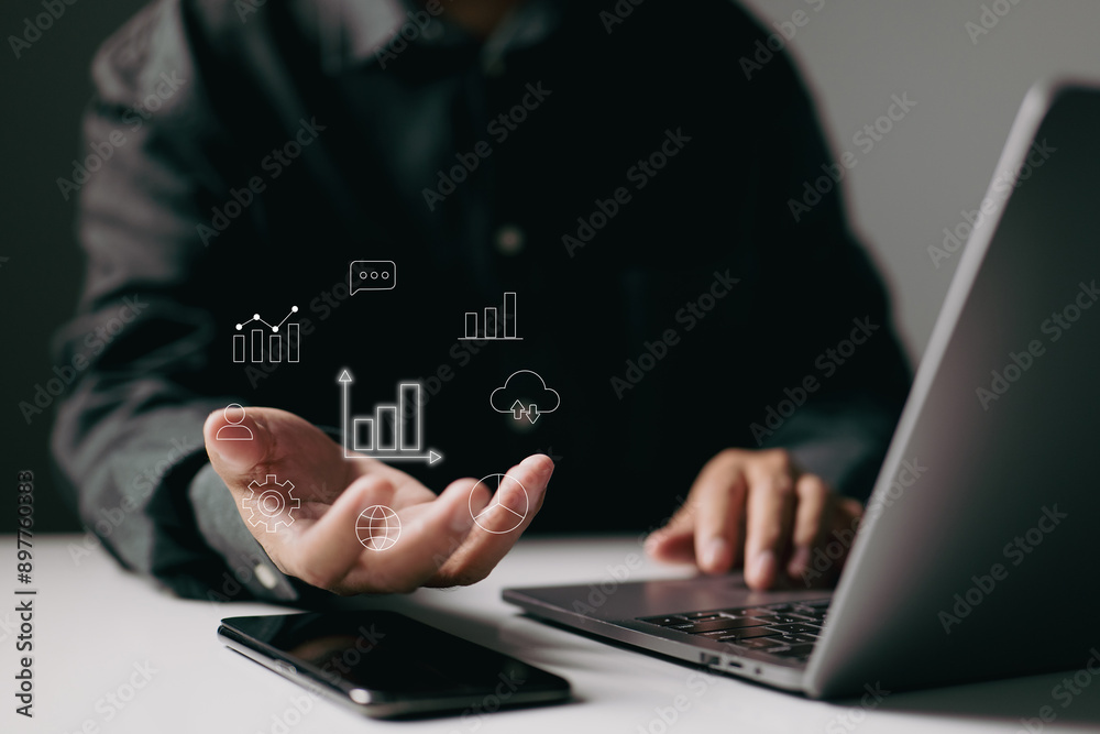 Poster person using a laptop with data icons hovering above their hand, symbolizing the integration of digital technology and data analysis in business.