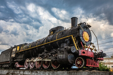 Old black steam locomotive against a cloudy dramatic sky. Vintage railway train. The Soviet locomotive class FD 20-2238 in Kharkiv city, Ukraine
