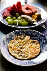 Morning food with fried egg papaya watermelon grape and bananas inside a plate. Healthy eating.