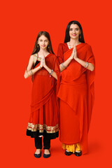 Beautiful mother with her daughter in sari on red background. Divaly celebration
