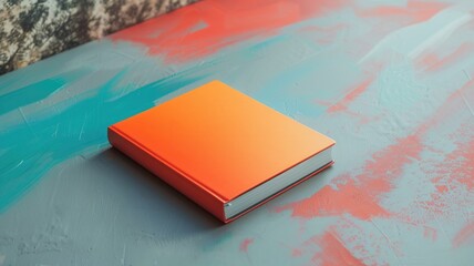 Orange book on multicolored painted surface