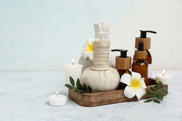 Set of spa supplies with different cosmetic products, herbal bags, plumeria flowers and burning candles on white background