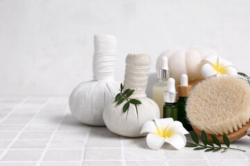 Set of spa supplies with bottles of cosmetic oil, herbal bags, massage brush and plumeria flowers...