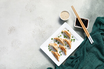 Plate with fried Japanese gyoza and bowl of soy sauce on grunge background