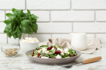 Plate of healthy vegetable salad with beet, feta cheese, arugula and pumpkin seeds on white grunge table