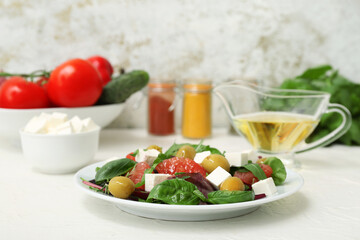 Plate of healthy vegetable salad with feta cheese, grapefruit, olives and basil on white table