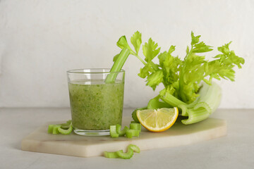 Glass of celery juice with celery and lemon on white background