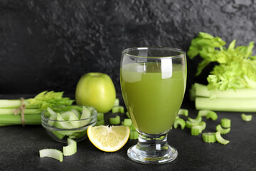 Glass of celery juice with chopped and whole celery, apple and lemon on black background