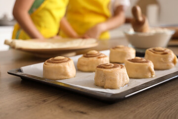 Tray with raw cinnamon rolls on table in kitchen, closeup