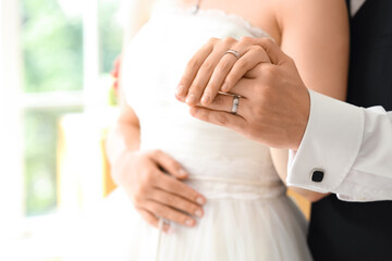 Young couple with rings holding hands on their wedding day, closeup