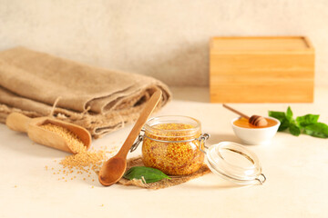Jar with Dijon mustard and bowl of honey on beige background