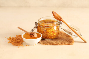 Jar with Dijon mustard and bowl of honey on beige background