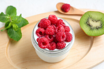 Jar of tasty yogurt with fresh raspberries and kiwi on white background