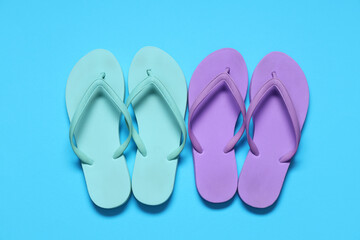 Different stylish flip-flops on blue background
