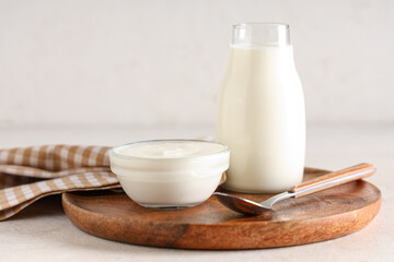 Glass bowl and bottle of tasty yogurt on white background