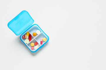 Blue plastic container with pills on white background. Top view