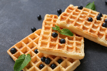Sweet Belgian waffles with fresh currants and mint on black background