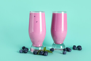 Glasses of fresh blueberry smoothie with mint and berries on turquoise background