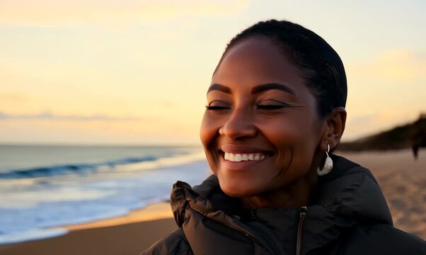 Portrait video of a pleased Nigerian black woman in her 50s wearing a warm parka against a beach background 