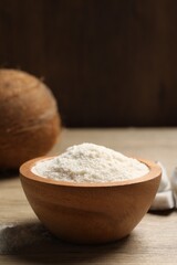 Fresh coconut flour in bowl and nut on wooden table
