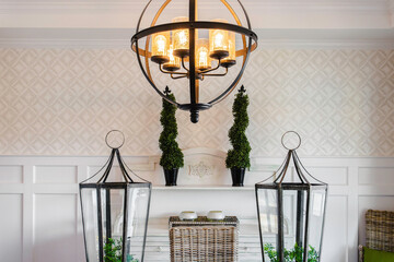 Sophisticated Dining Area With Chandelier, Wicker Furniture, And Green Topiaries.