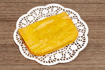 A flaky Jamaican spicy beef, chicken or veggie patty on a white paper doily