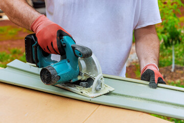 Working with circular handsaw, worker cuts plastic vinyl siding to desired size before installing it