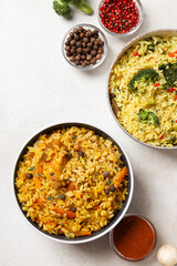 Pilaf in bowls and red pepper on white background, top view