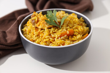Pilaf in bowl and towel on white background, close up