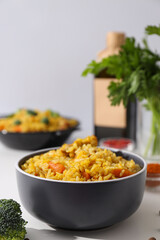 Pilaf in bowls, spices and bottle on white background, close up