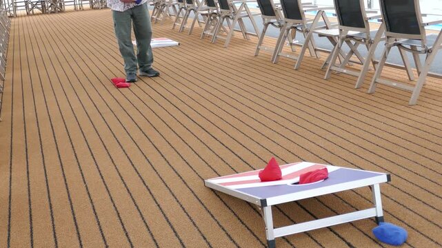 Man on cruise ship deck playing corn hole recreational game