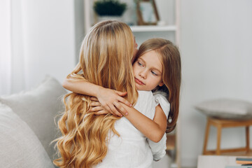 Young girl embracing her mother on cozy living room sofa in warm and inviting home environment