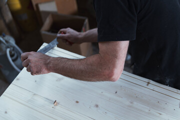 Carpenter using hand plane on wood plank in workshop