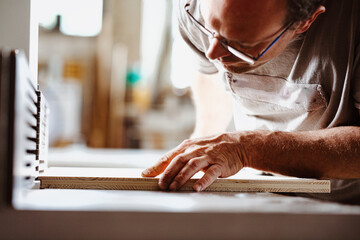 Senior carpenter examining wood plank in workshop