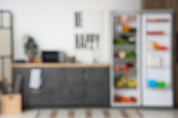 Open big fridge with fresh products in kitchen. Blurred view