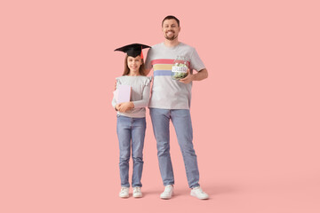 Father and his daughter in mortar board with books and money jar on pink background. Tuition fees concept