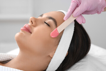 Beautician with wax removing woman's hair in salon, closeup