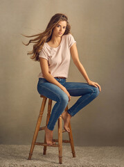 Woman, hair care and studio portrait with wind for growth, textures and casual fashion on stool....