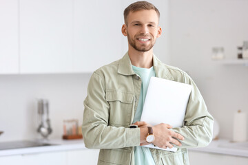 Young bearded man with laptop in kitchen