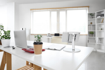 Interior of stylish office with workplace, laptop and houseplant