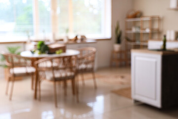 Paper shopping bag with different fresh green vegetables and fruits on table in kitchen, blurred view