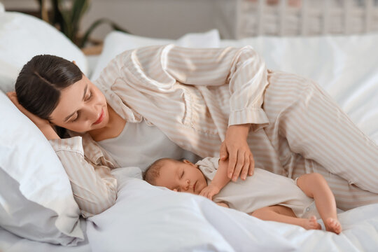 Mother with her little baby lying in bedroom