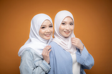Two beautiful Malaysian and Indonesian Muslim young women wearing modern and casual wear with hijab on isolated studio background. Modern hijab fashion and beauty concept