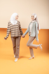 Two beautiful Malaysian and Indonesian Muslim young women wearing modern and casual wear with hijab on isolated studio background. Modern hijab fashion and beauty concept