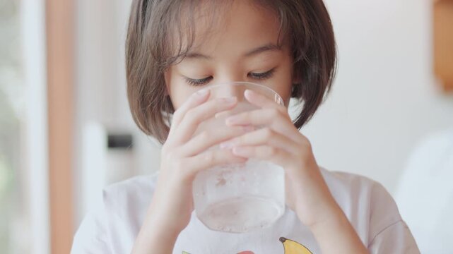 Face close up of adorable Asian girl is drinking water, healthy lifestyle of hydration for her thirst with pure water highlight the simplicity and necessity of this daily routine for refreshment.