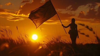 Silhouetted figure holding national flag against vivid sunset landscape
